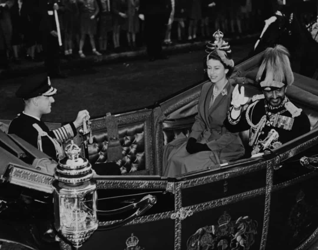 Hoàng đế Haile Selassie của Ethiopia vẫy chào người dân khi ông ngồi trên xe ngựa cùng Nữ hoàng Elizabeth II và Hoàng thân Philip, tại Anh năm 1954.