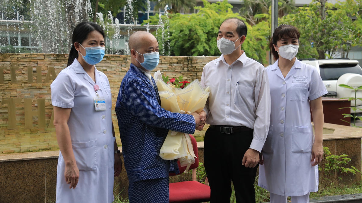Ông Nguyễn Đình Hưng, Phó Giám đốc Sở Y tế Hà Nội và đại diện lãnh đạo Bệnh viện Thanh Nhàn trao hoa chúc mừng bệnh nhân Covid-19 khỏi bệnh.