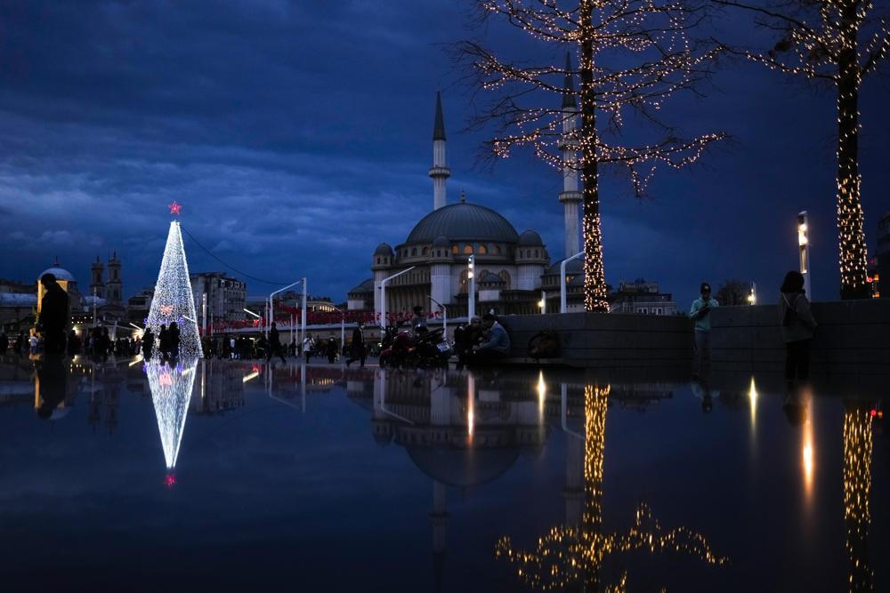 Người dân đi bộ qua cây thông Noel bên cạnh nhà thờ Hồi giáo Taksim tại quảng trường Taksim ở thành phố Istanbul, Thổ Nhĩ Kỳ. Ảnh: AP.
