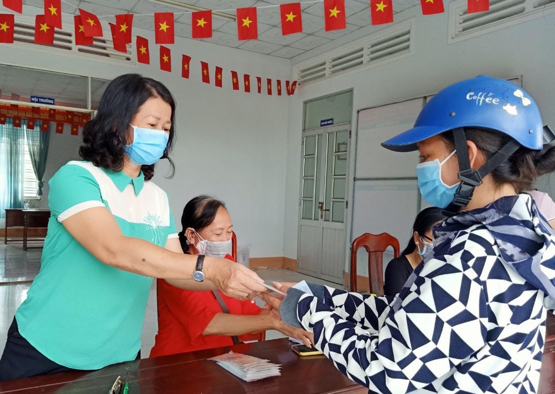 Đại diện MTTQ quận Thốt Nốt chi hỗ trợ tiền cho người bán vé số lẻ.