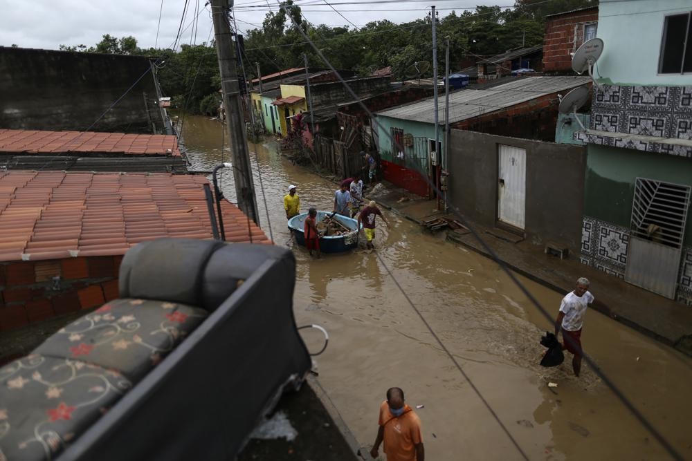 Người dân thu dọn đồ đạc giữa trận lụt ở thành phố tự trị Itapetinga, bang Bahia, Brazil. Ảnh: AP.