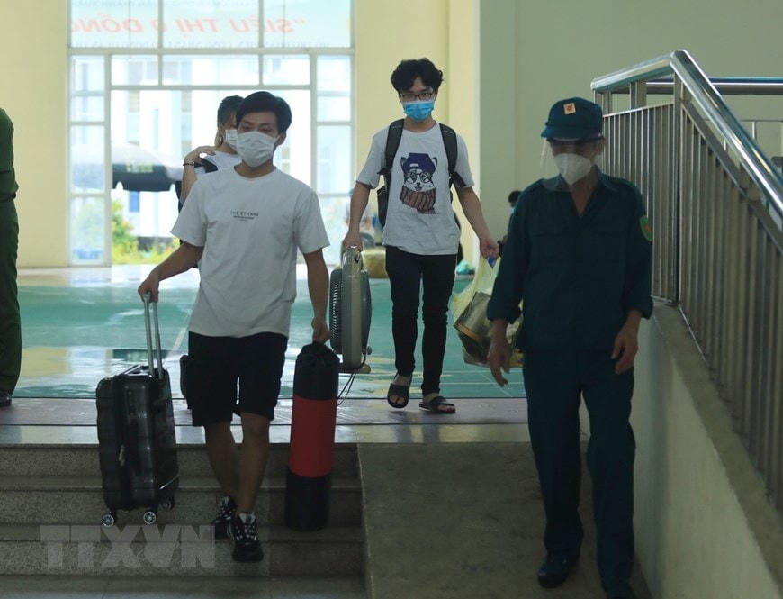 Lực lượng chức năng hỗ trợ người dân trở về sau khi hoàn thành cách ly 21 ngày. (Ảnh: Tuấn Anh/TTXVN)