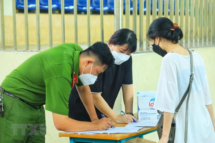 Lực lượng chức năng kiểm tra danh sách những người được đưa về. (Ảnh: Tuấn Anh/TTXVN)