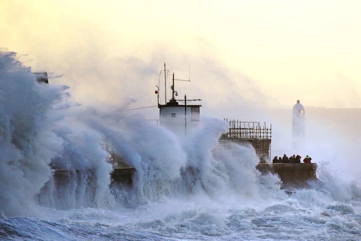 Sóng vỗ vào bức tường biển và ngọn hải đăng Porthcawl. Ảnh: Jacob King / PA.