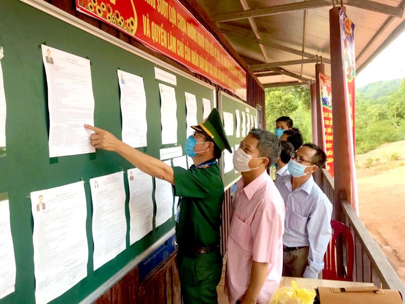 Bộ đội biên phòng và bà con ở xã Thượng Trạch (huyện Bố Trạch) tìm hiểu các ứng cử viên trước khi ghi phiếu bầu. Ảnh: Báo Nhân Dân.  