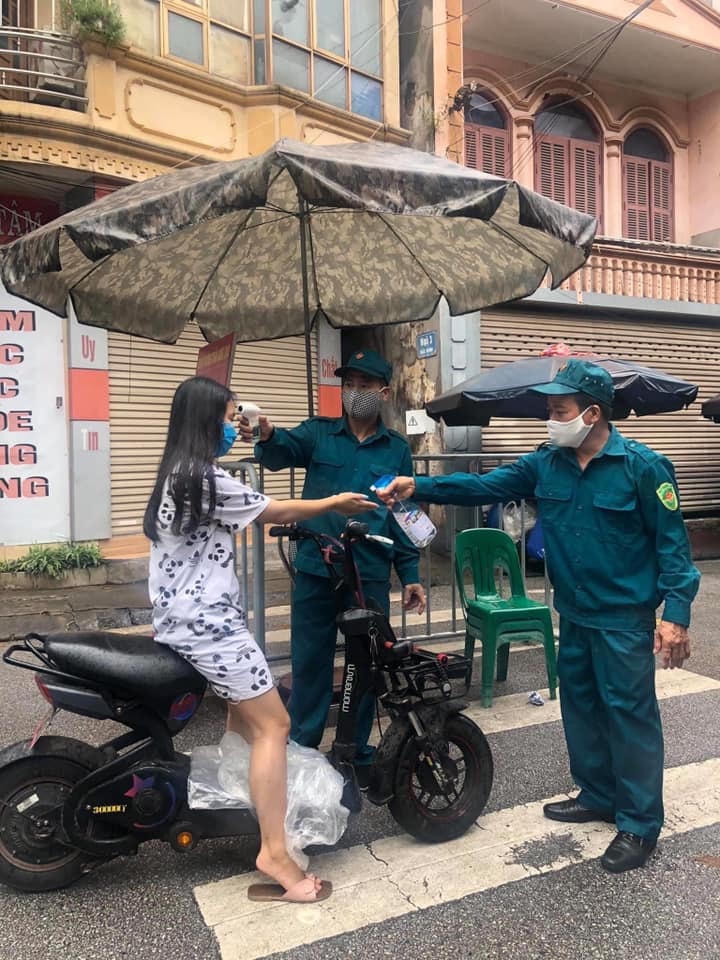 Lực lượng chức năng đo thân nhiệt, xịt khuẩn cho người dân.