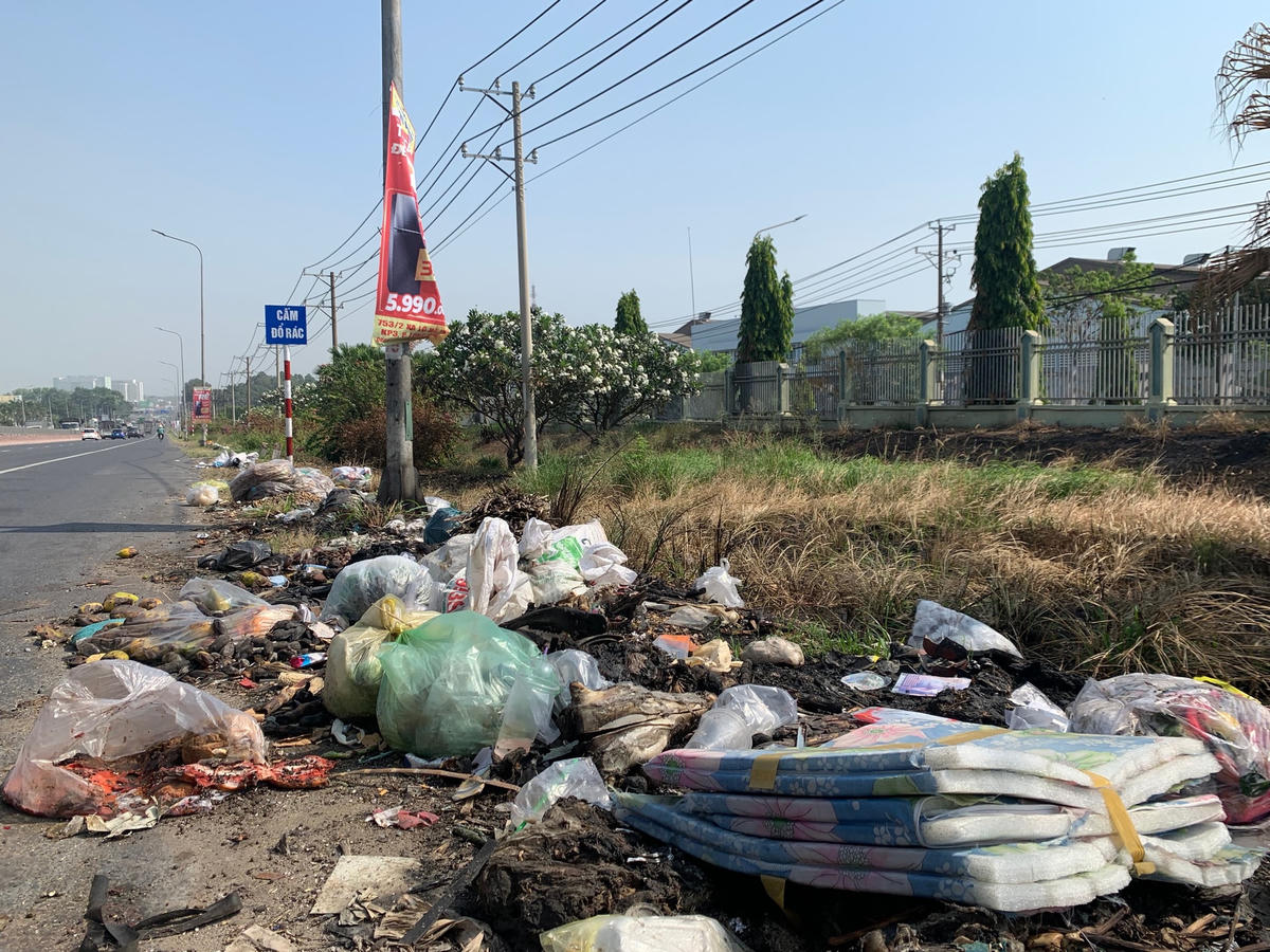 Một điểm tập kết rác tự phát trên Quốc lộ 1A (phường An Bình). Cách đó không xa là một tấm biển cảnh báo “cấm đổ rác”.