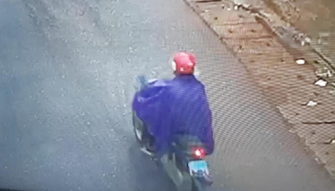 Đối tượng Phạm Văn Sỹ đi xe máy, mặc áo mưa sau khi cướp được tiền tại ngân hàng.