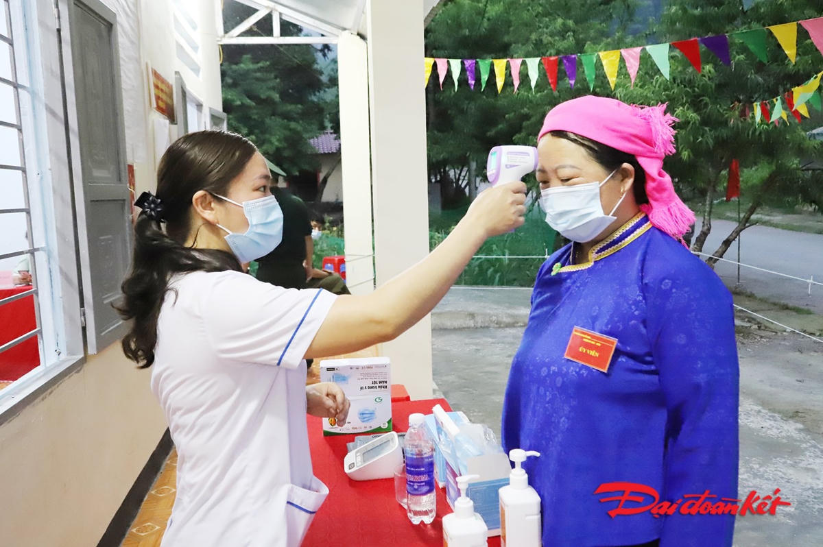 Các cử tri được cán bộ Tổ bầu cử hỗ trợ đeo khẩu trang đúng quy cách, kiểm tra thân nhiệt và sát khuẩn trước khi thực hiện bầu cử. Ảnh: Minh Đức. 