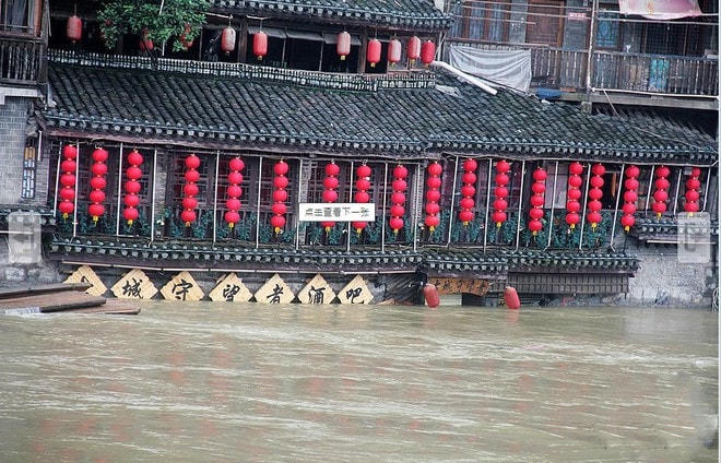 Cảnh nhiều ngôi nhà nằm hai bên bờ sông Đà Giang ở Phượng Hoàng cổ trấn chìm trong nước lũ hôm 27/6. (Ảnh chụp màn hình China News).