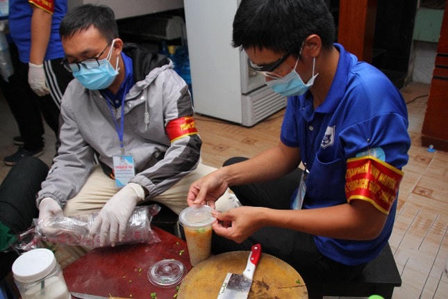 Các bạn tình nguyện viên đậy nắp ly cháo thật chắc chắn để dễ mang đi phát cho người dân.