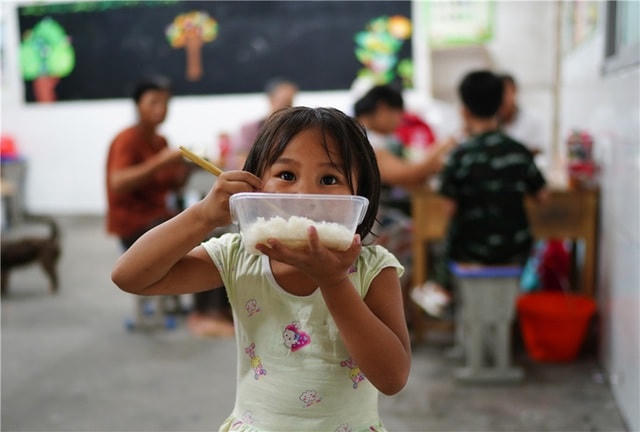 Một bé gái ăn cơm tại nơi trú ẩn tạm cho người dân ở Bà Dương, Giang Tây hôm 9/7 (Ảnh: Tân Hoa Xã).