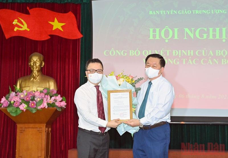 Trưởng ban Tuyên giáo Trung ương Nguyễn Trọng Nghĩa trao quyết định và tặng hoa, chúc mừng ông Lê Quốc Minh. Ảnh: Nhân Dân.