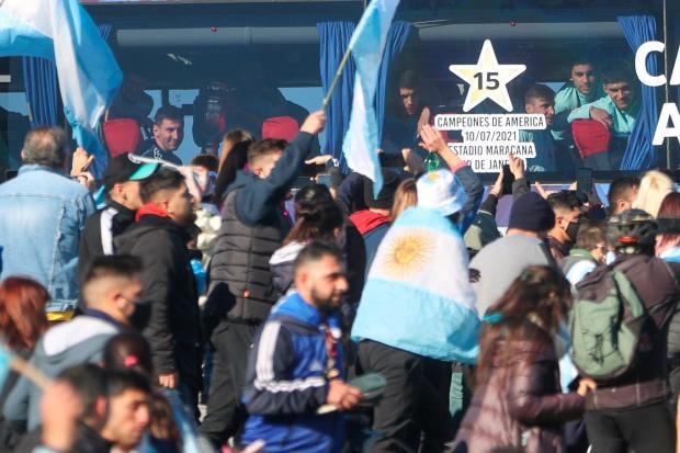 Những CĐV Argentina vẫy quốc kỳ chào đón các cầu thủ. Trên xe bus của đội tuyển Argentina có dòng chữ ghi nhớ về trận chung kết Copa America với Brazil vào ngày 10/7 tại sân Maracana.