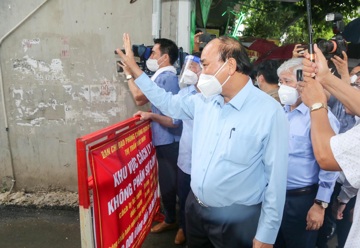 Chủ tịch nước Nguyễn Xuân Phúc và Chủ tịch UBTƯ MTTQ Việt Nam Đỗ Văn Chiến hỏi thăm người dân tại một khu phong tỏa ở khu phố 1, thị trấn Hóc Môn, huyện Hóc Môn, TP HCM. Nguồn: Tuổi trẻ.