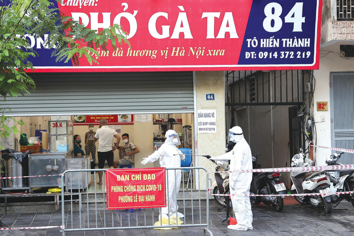 Nhân viên y tế quận Hai Bà Trưng tiến hành phun khử khuẩn và lấy mẫu xét nghiệm tại một quán ăn có ca dương tính đến ăn.