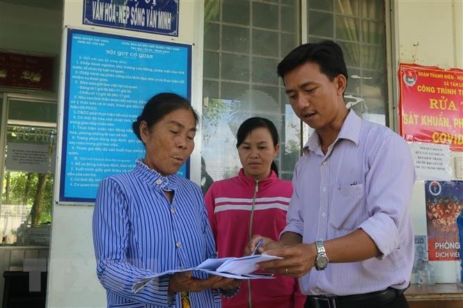 Cán bộ xã Tân Long (sáp nhập từ 2 xã Tân Lập và Long Thành), thuộc huyện Thủ Thừa, hướng dẫn người dân làm thủ tục hành chính. (Ảnh: Thanh Bình/TTXVN).