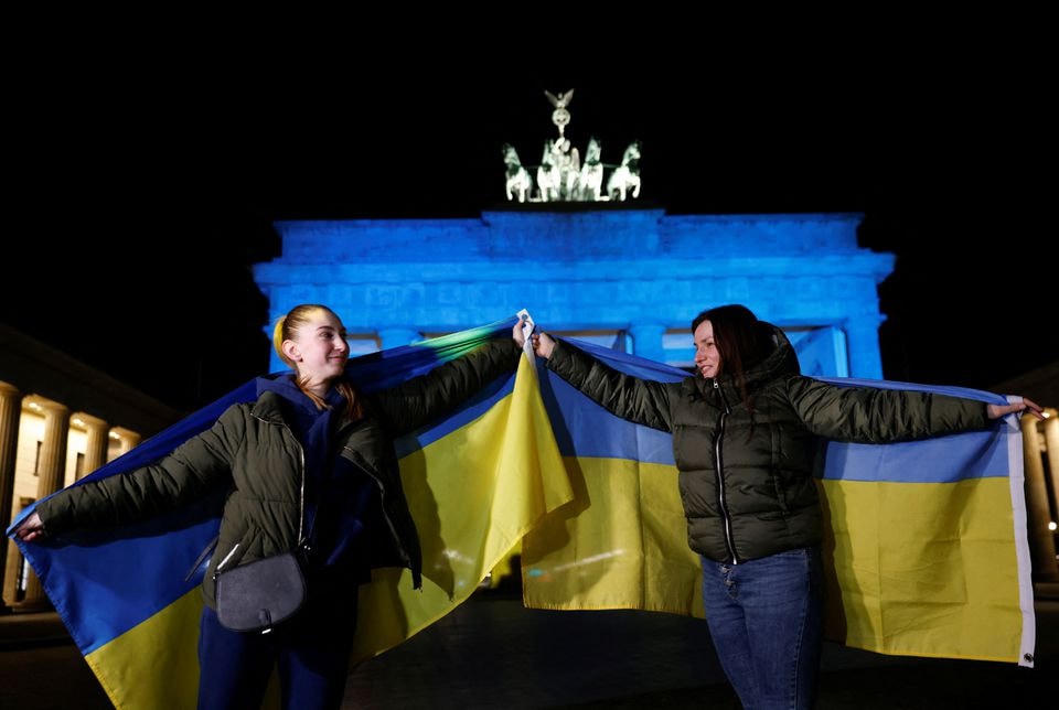 2 người phụ nữ giơ cao quốc kỳ Ukraine ngay trước Cổng Brandenburg. Ảnh: Reuters / Michele Tantussi. 