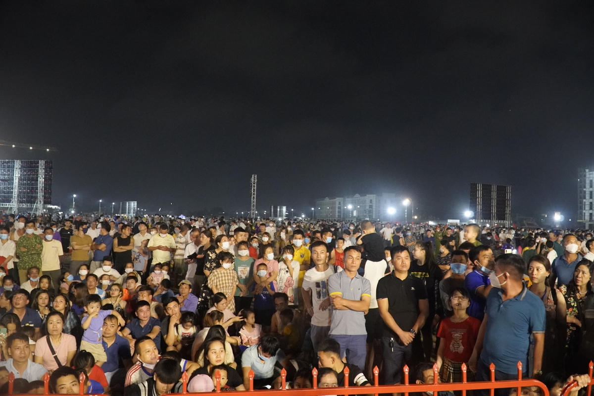 Sau dãy rào sắt, người dân vừa đứng vừa ngồi để chờ đợi đến thời khắc lễ khai mạc bắt đầu.