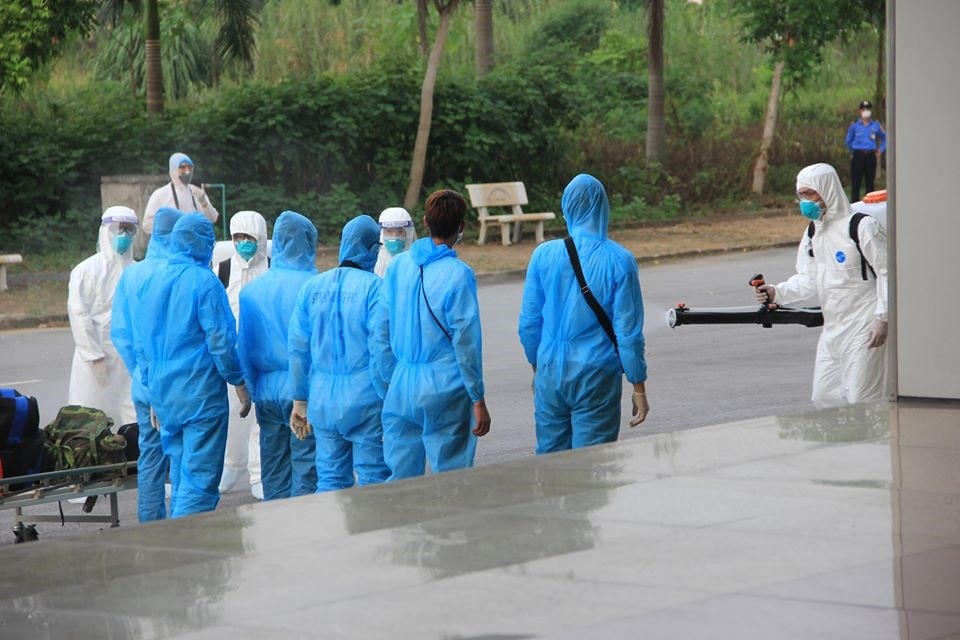 Khử khuẩn cho các công dân từ Guinea Xích đạo về trước khi vào khu cách ly tại bệnh viện. (Ảnh: PV/Vietnam+).