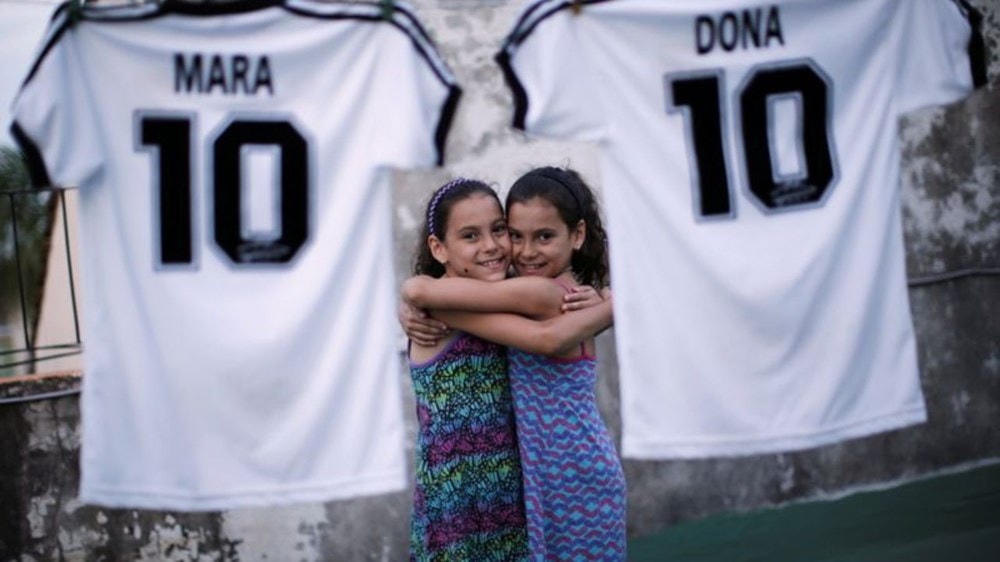Hai bé gái song sinh Mara và Dona cùng chiếc áo số 10 của thần tượng Diego Maradona. (Ảnh: Reuters).
