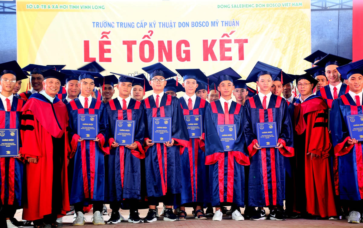 Linh mục Vũ Kim Long trao bằng chứng nhận hoàn thành chương trình phổ thông cho các em học sinh. 
