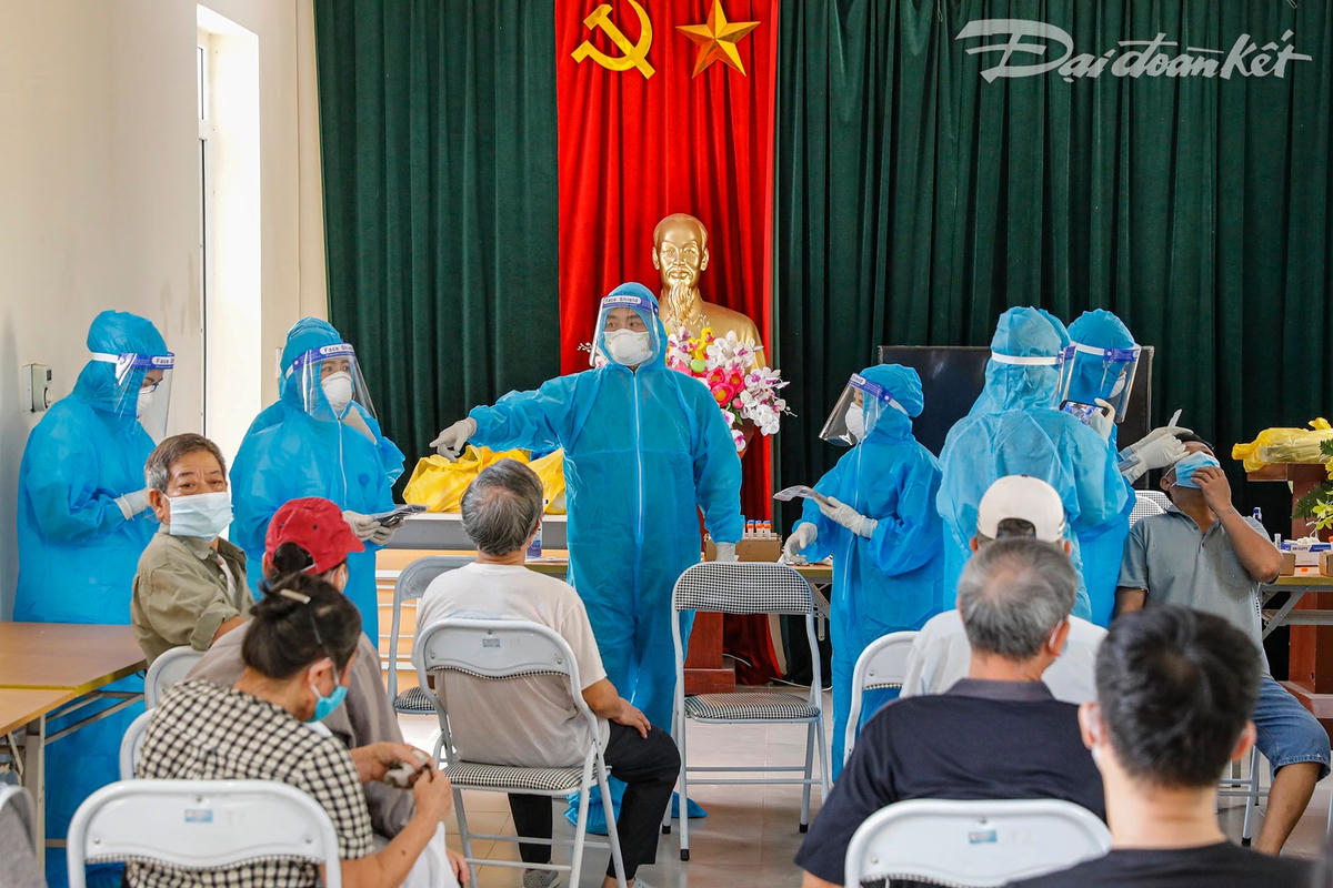 Nhân viên y tế chia làm 2 bàn thực hiện lấy mẫu xét nghiệm, mỗi bàn sẽ có một người lấy mẫu, một người phụ trách quét mã QR code và người hỗ trợ. Ảnh: Quang Vinh. 