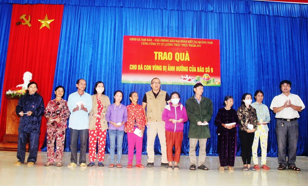 Chủ tịch UBND xã Tam Dân (bìa phải) trao quà cho bà con.