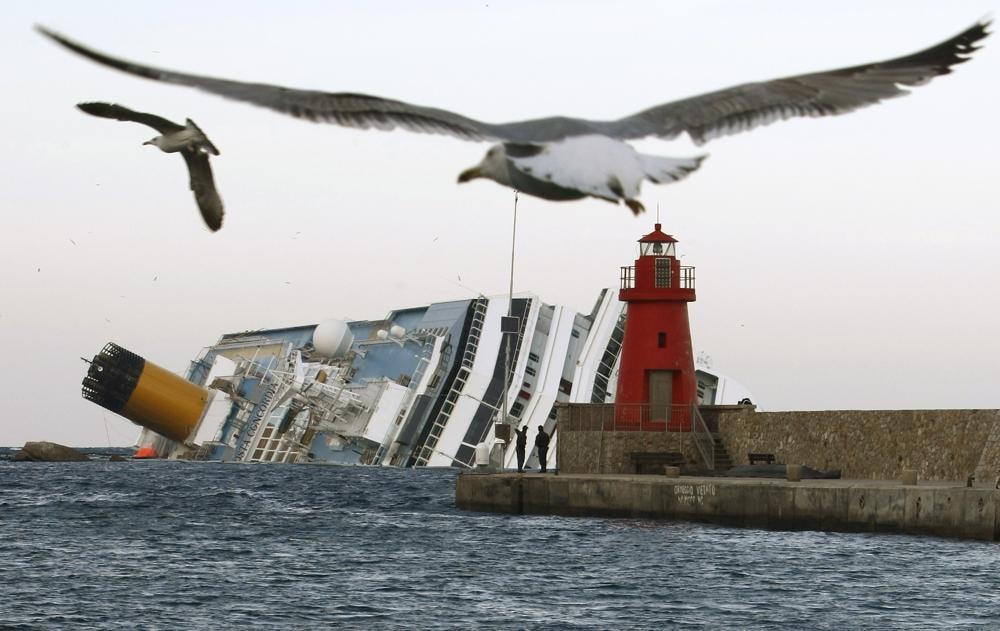 Những con mòng biển bay phía trước xác con tàu du lịch Costa Concordia ngoài khơi đảo Isola del Giglio ngày 30/1/2012. Ảnh: AP.