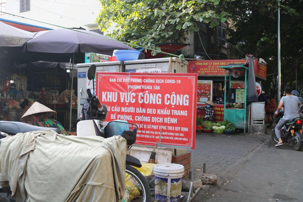 Biển báo nhắc nhở đeo khẩu trang bị “kẹp giữa” và “lấp ló” sau hàng xe máy và bốt điện.