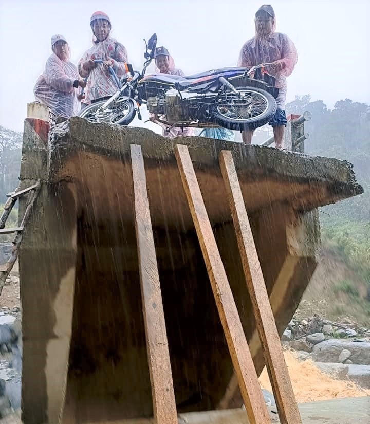 Người dân đưa xe qua đoạn cây cầu hư hỏng ở xã Phước Lộc.