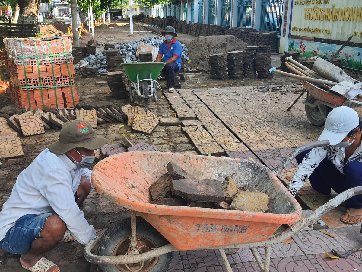 Công nhân tranh thủ lát gạch vỉa hè ở điểm trường mầm non trên địa bàn thành phố thuận tiện các em học sinh đi lại, tạo vẻ mỹ quan đô thị. 