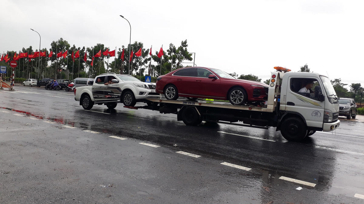 …Trong khi đó hai chiếc xe ô tô phải nhờ xe cứu hộ để qua vùng nước ngập.