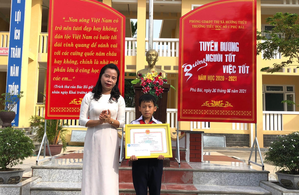 Bà Ngô Thị Ái Hương, Trưởng phòng GD&ĐT thị xã Hương Thuỷ tặng Giấy khen cho em Hưng.