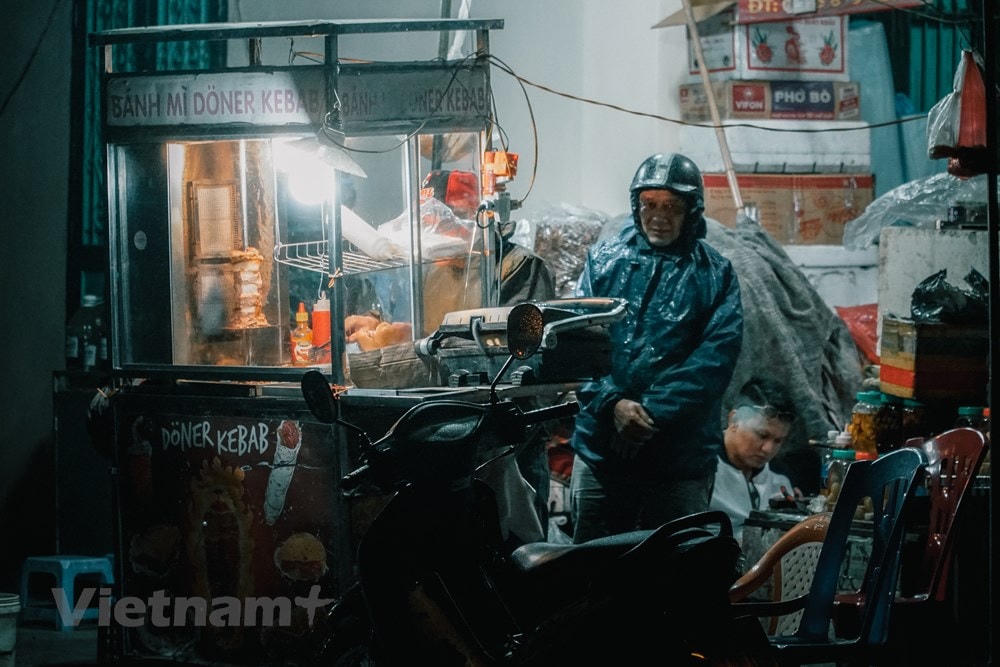 Xe bán bánh mỳ của người lao động vẫn sáng đèn trong đêm. (Ảnh: Minh Hiếu/Vietnam+).