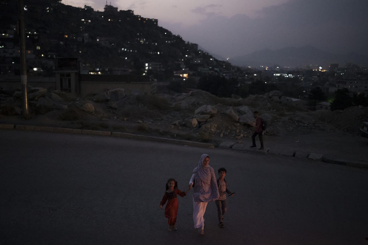 Một gia đình Afghanistan băng qua đường lúc hoàng hôn ở thủ đô Kabul, Afghanistan (19/9/2021). Ảnh: AP.