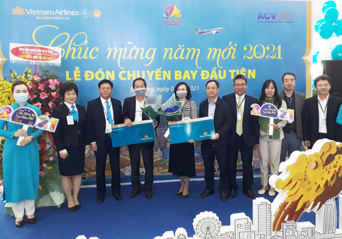 Lãnh đạo Sở Du lịch Đà Nẵng, Cảng hàng không quốc tế Đà Nẵng và Vietnam Airlines trao quà tặng may mắn cho 2 khách đầu tiên của năm 2021. Ảnh Thanh Tùng.