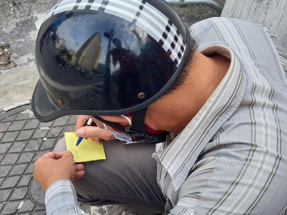 Một người dân đang ghi thông tin người thân để gửi đồ. 