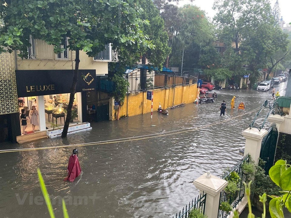 Người dân phải lội bì bõm trong dòng nước bẩn. (Ảnh: Vietnam+).