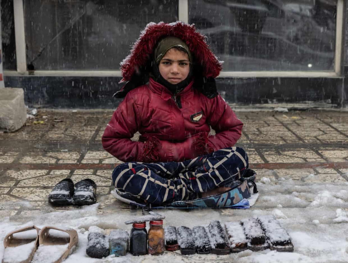 Cô bé Khadjia với đồ nghề kiếm sống dưới trời tuyết trắng xóa ở thủ đô Kabul, Afghanistan. Ảnh: The Guardian.