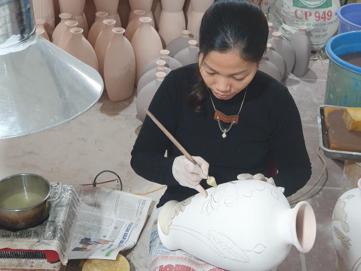 Nghệ nhân làng nghề gốm Bát Tràng trang trí họa tiết cho sản phẩm.