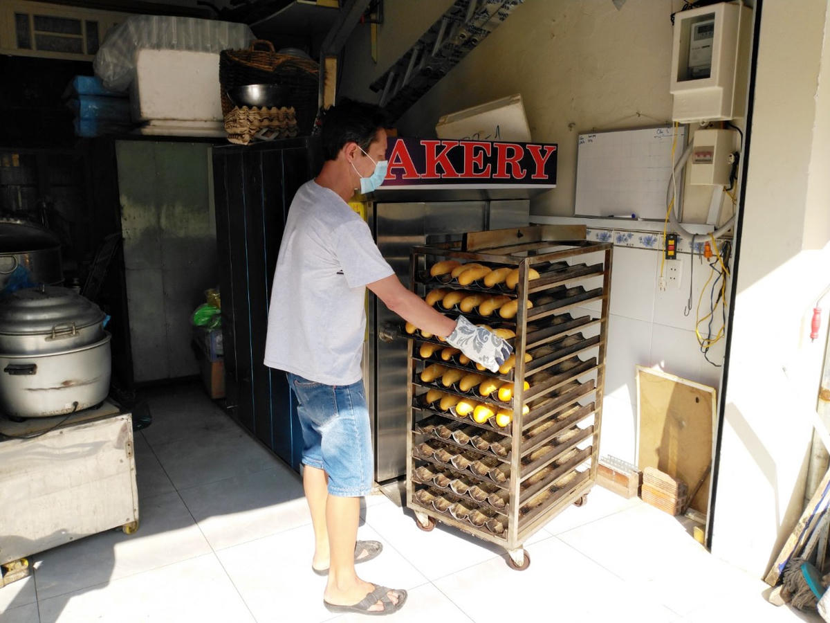 Anh Trần Hoàng Quân, chủ lò bánh mì Hoàng Quân, TP Thủ Đức đang cho ra lò mẻ bánh mì đầu tiên sau hai tháng ngưng sản xuất.