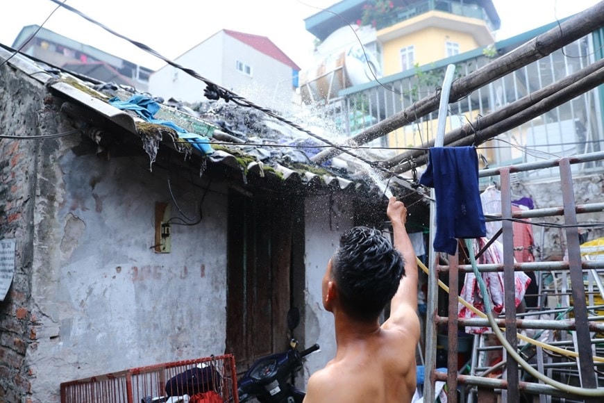 Trước cái nóng như rang, người lao động ở xóm trọ Phúc Xá phải phun nước liên tục lên mái nhà để giảm nhiệt. (Ảnh: Thành Đạt/TTXVN).