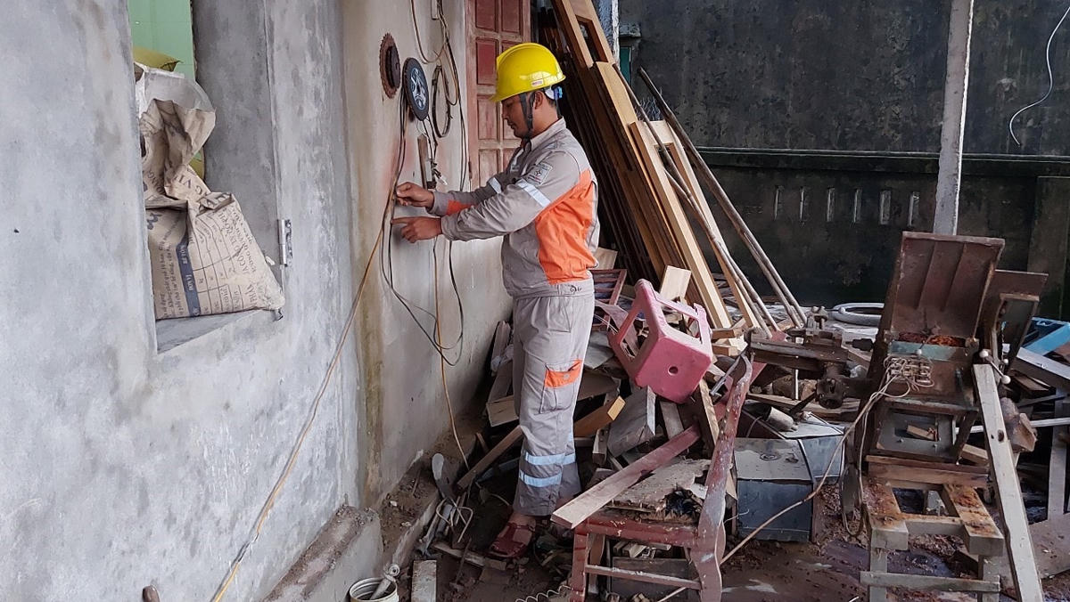 Công nhân Điện lực Cẩm Xuyên hỗ trợ kiểm tra thiết bị điện trong nhà cho người dân.
