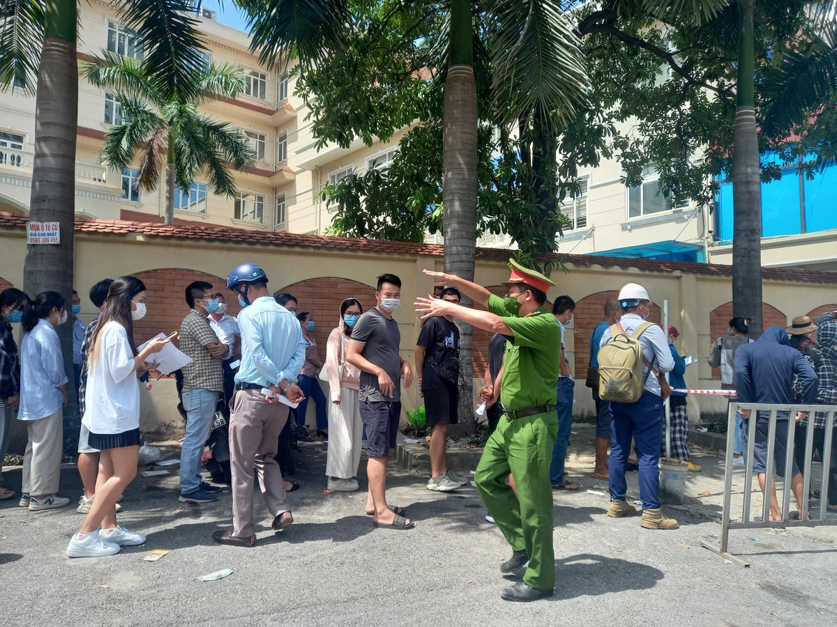 Lưc lượng chức năng nhắc nhở người dân xếp hàng, tuân thủ đúng quy định giãn cách. 