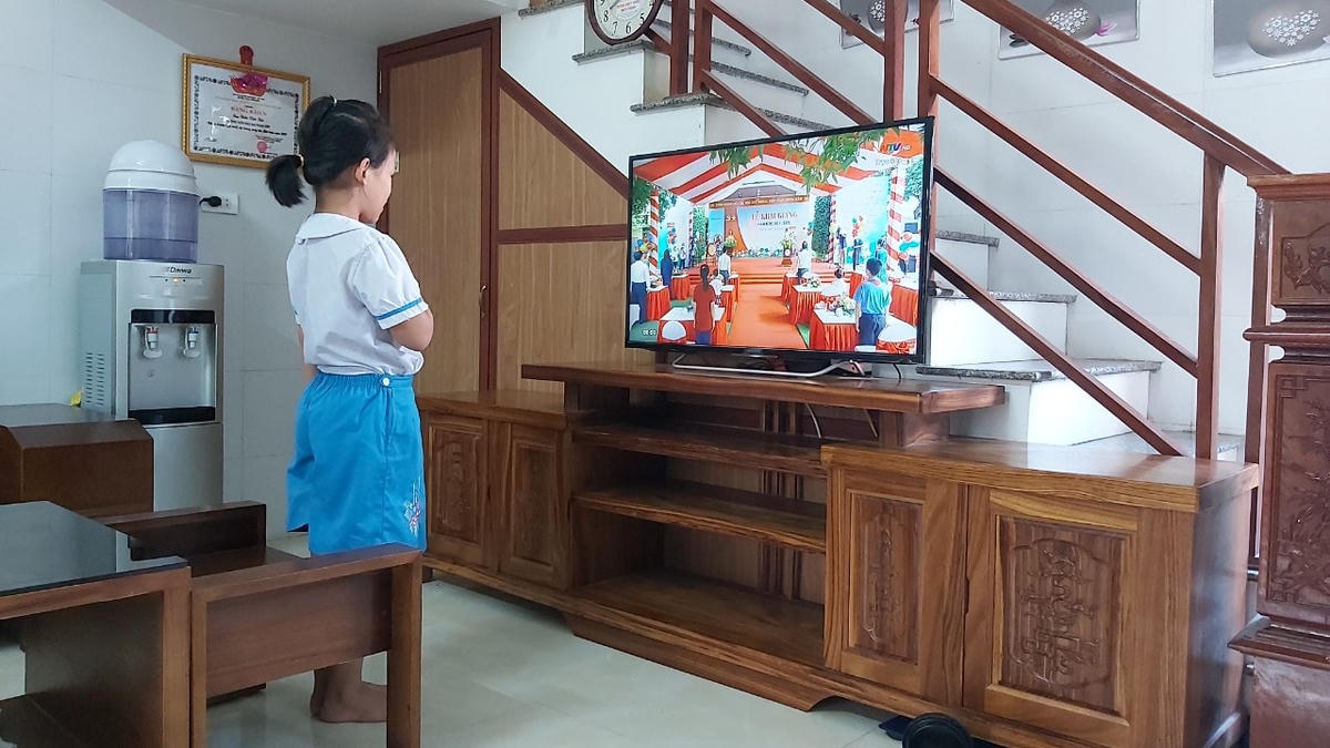 Cháu Trúc Ly, học sinh lớp 3G trường Tiểu học Hưng Dững 1, TP Vinh (Nghệ An) dậy từ sớm, đồng phục chỉnh tề dự lễ khai giảng qua chiếc ti vi của gia đình.