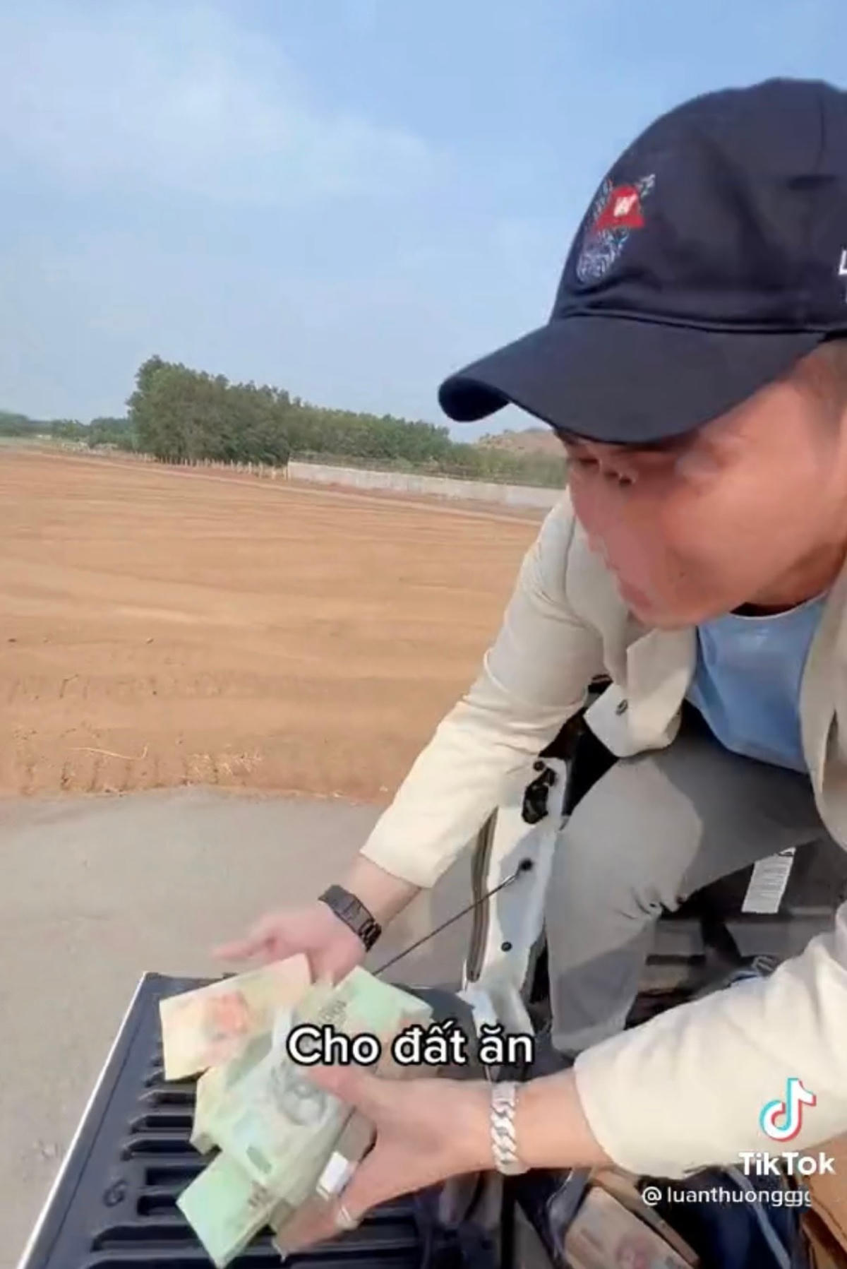 Nam thanh niên ngồi trên xe ô tô vứt tiền xuống đất.