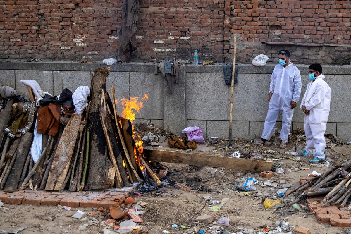 Người thân đứng cạnh một thi thể trên giàn thiêu tại New Delhi ngày 22/4. (Ảnh: Reuters).