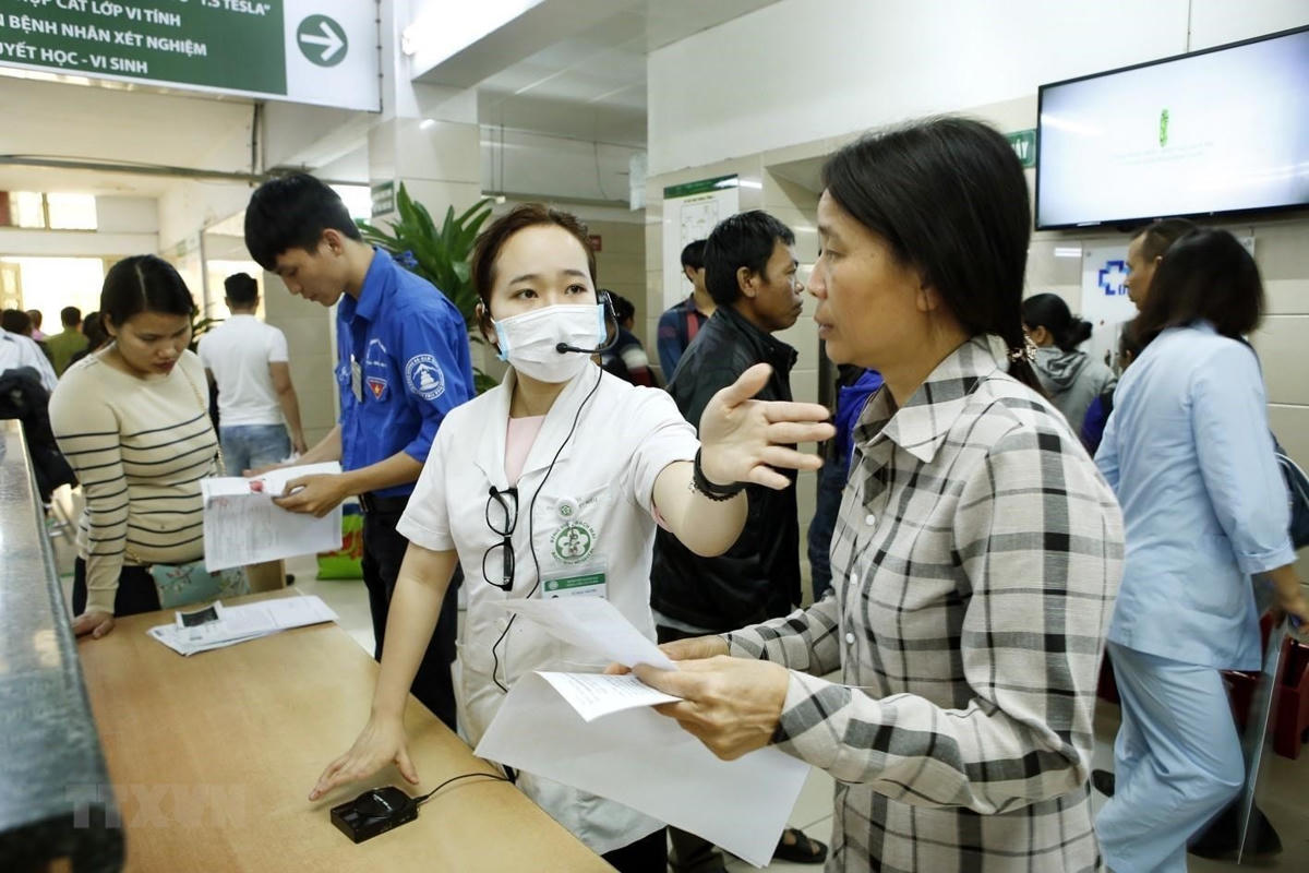 Nhân viên công tác xã hội hướng dẫn người bệnh làm thủ tục khám chữa bệnh tại Bệnh viện Bạch Mai. Ảnh: Dương Ngọc.