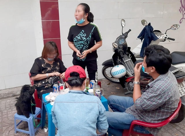 Nhóm người ngồi nhậu trên vỉa hè và không đeo khẩu trang bị lực lượng chức năng lập biên bản xử phạt hành chính.